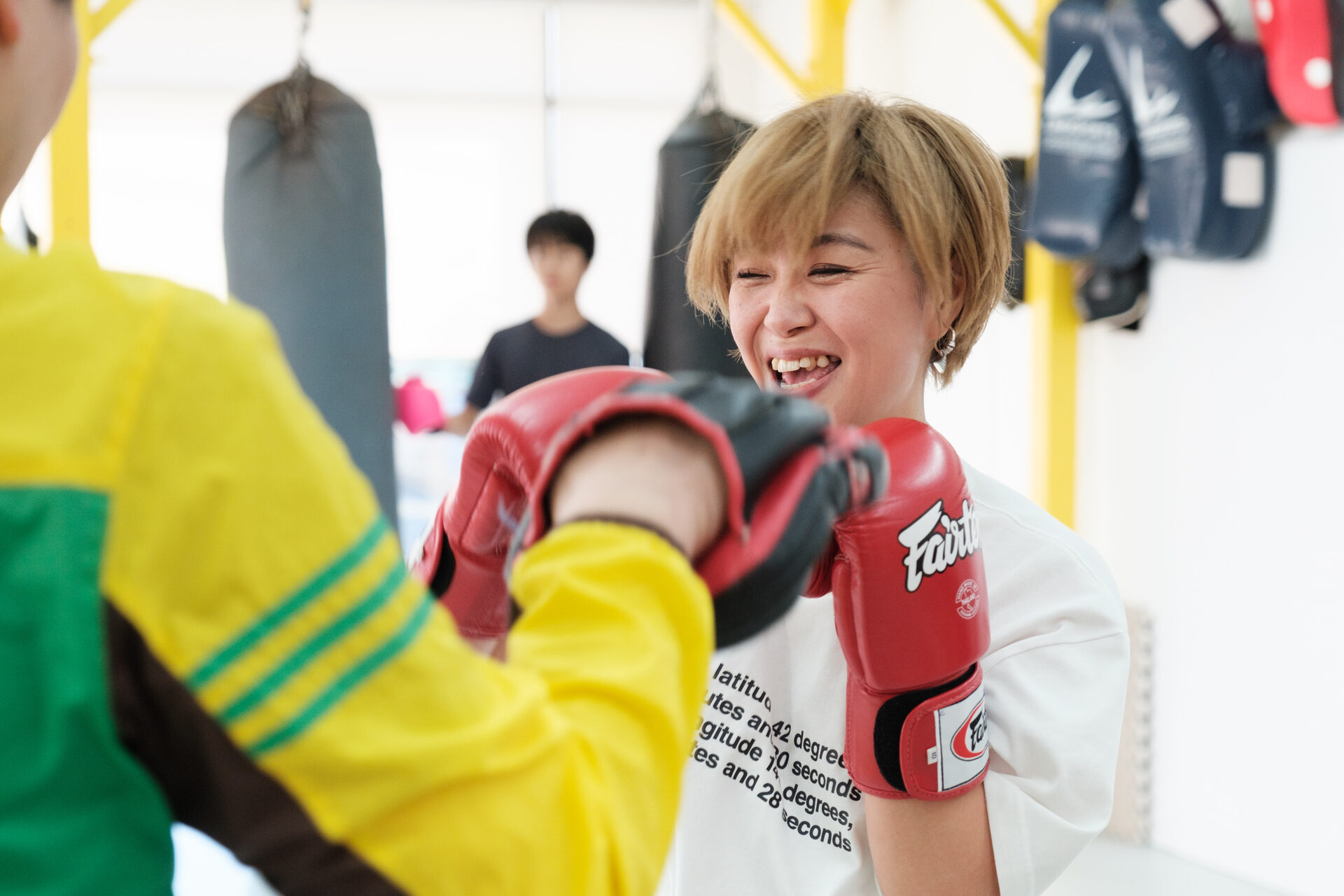 女性会員がインストラクターのミットに向かってパンチを打っている様子